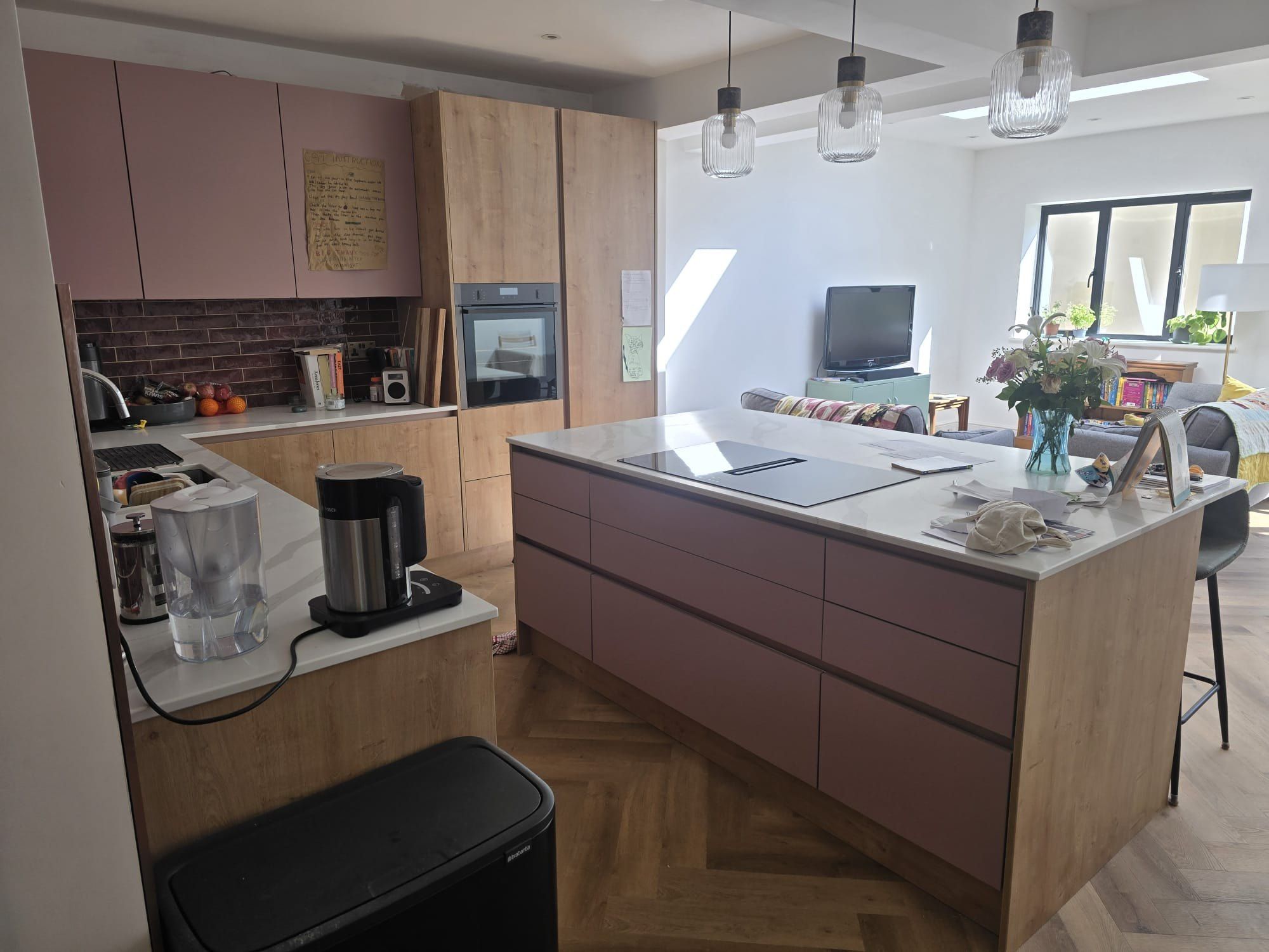 Pink and oak kitchen island under pendant lights